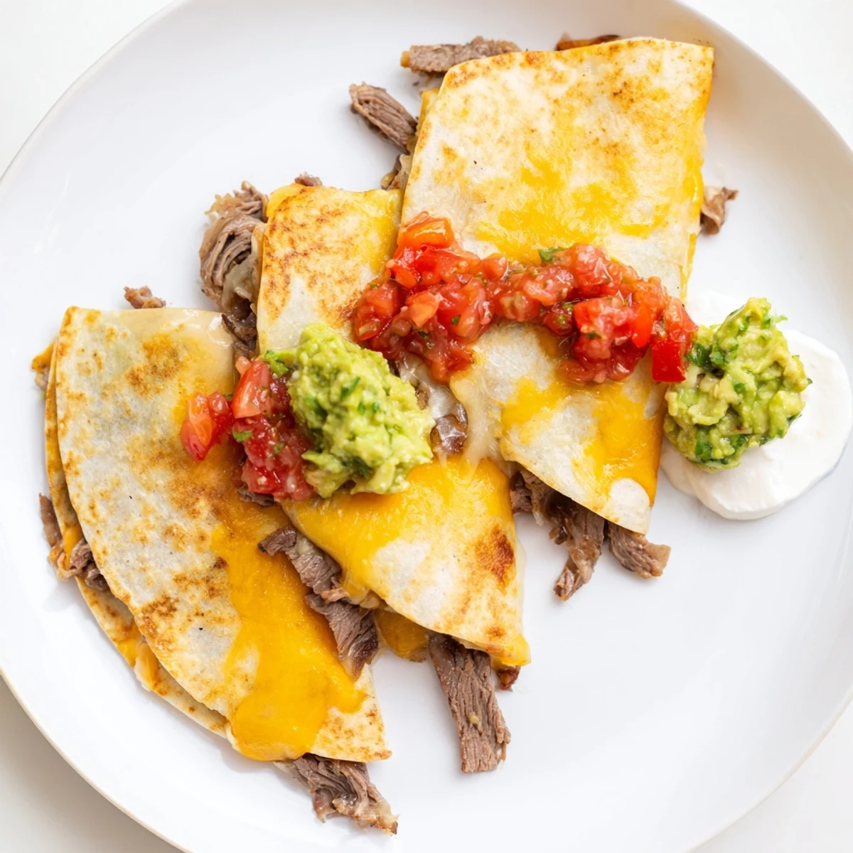 Hearty Tex-Mex Beef Quesadillas with golden-brown tortillas, fresh salsa, and sour cream on a rustic serving platter.