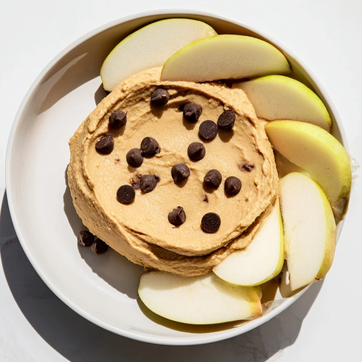 Healthy snack platter featuring Chocolate Chip Cookie Dough Hummus with red apple slices for a gluten-free treat.