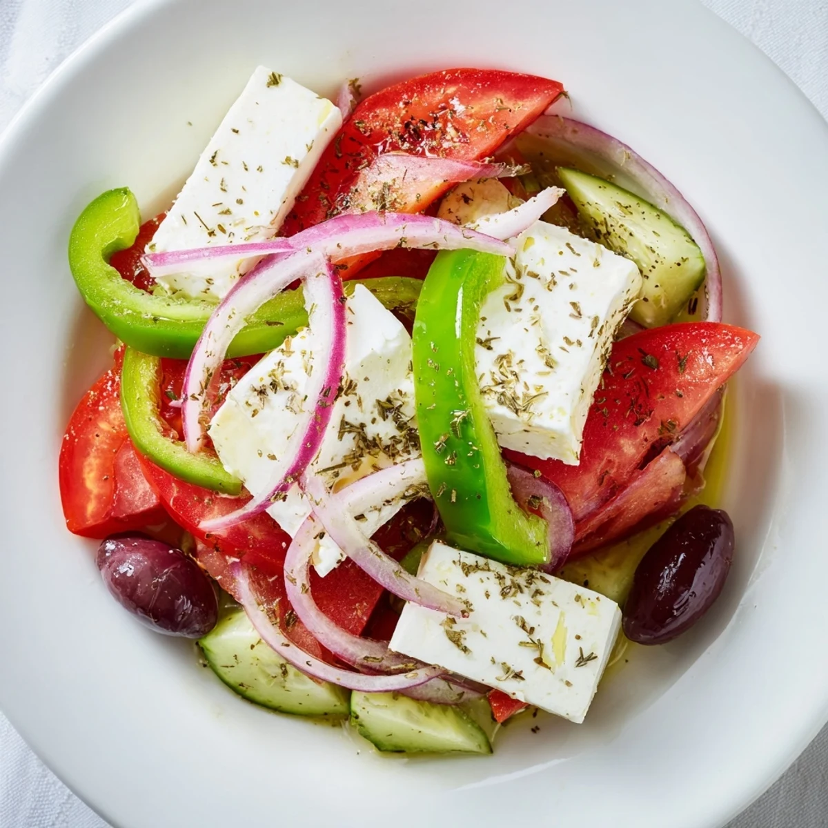 Bright, colorful Greek Salad with Kalamata olives, cucumber, and feta, served with a drizzle of dressing alongside warm grilled pita bread for dipping.