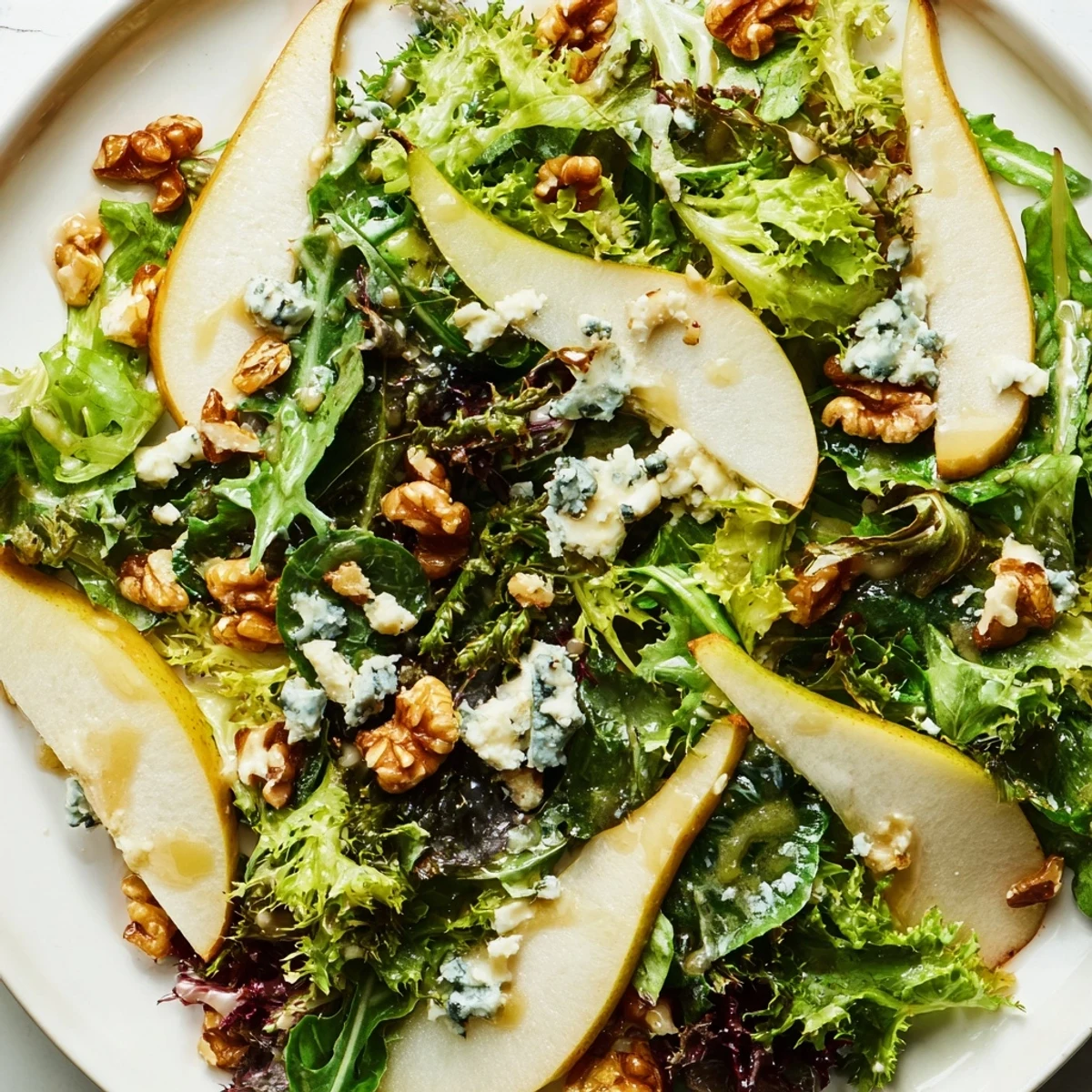 Close-up of Winter Green Salad with Pear and Candied Walnuts showing candied walnuts and greens, served with a fork.