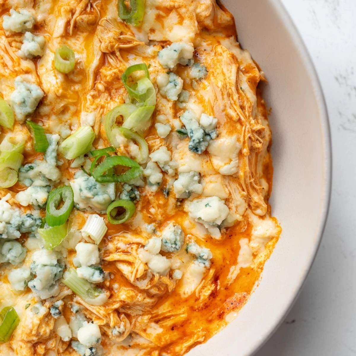 Golden, creamy Spicy Buffalo Chicken Dip in a skillet, ready for dipping celery and crunchy chips at a party.