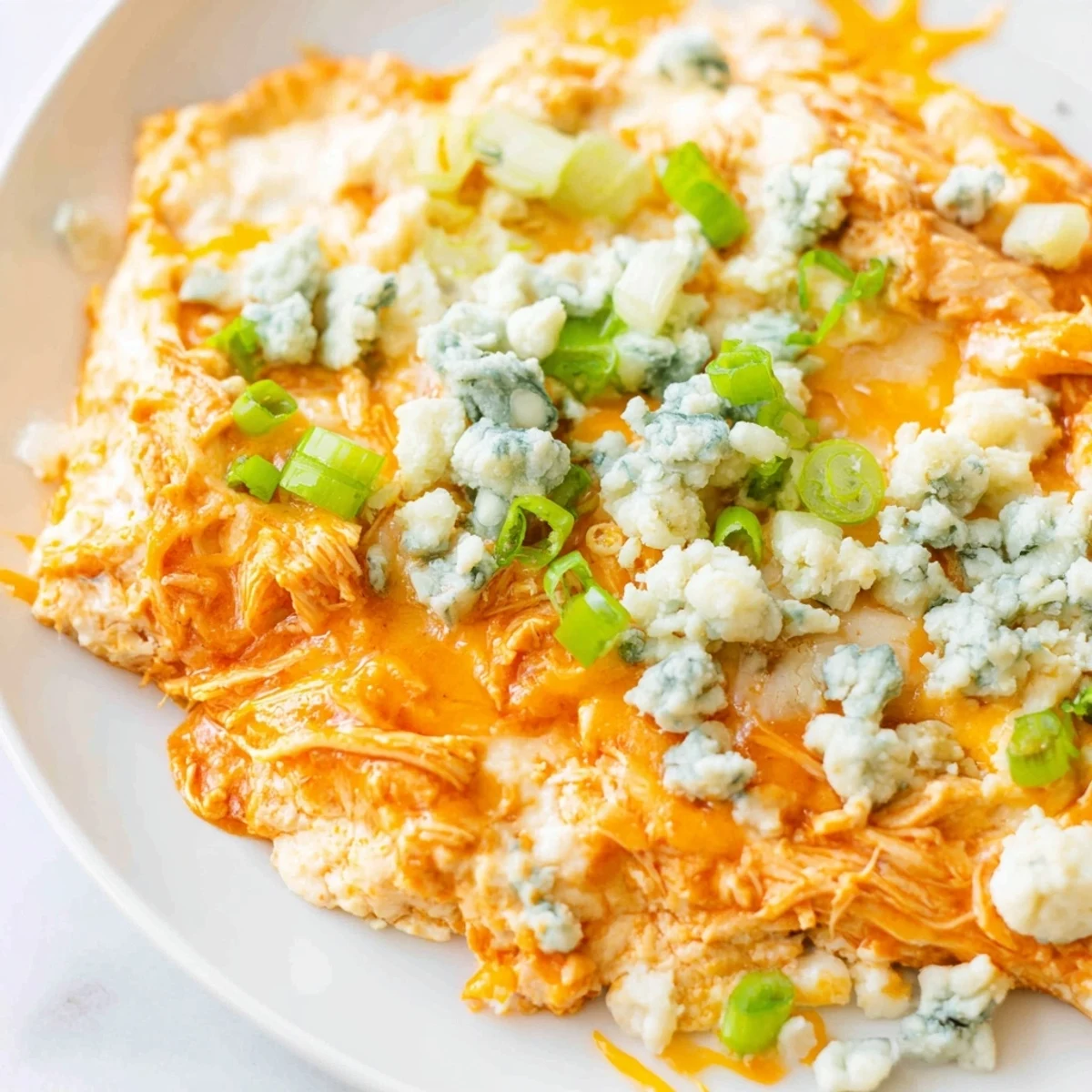 Freshly baked Spicy Buffalo Chicken Dip garnished with green onions, paired with celery sticks and chips for a game day snack.