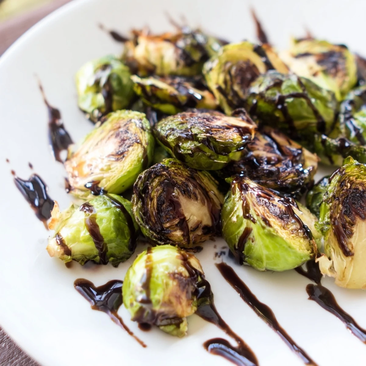 Freshly roasted Brussels Sprouts with Balsamic Glaze Reduction featuring crispy, caramelized leaves served alongside roasted chicken for dinner.