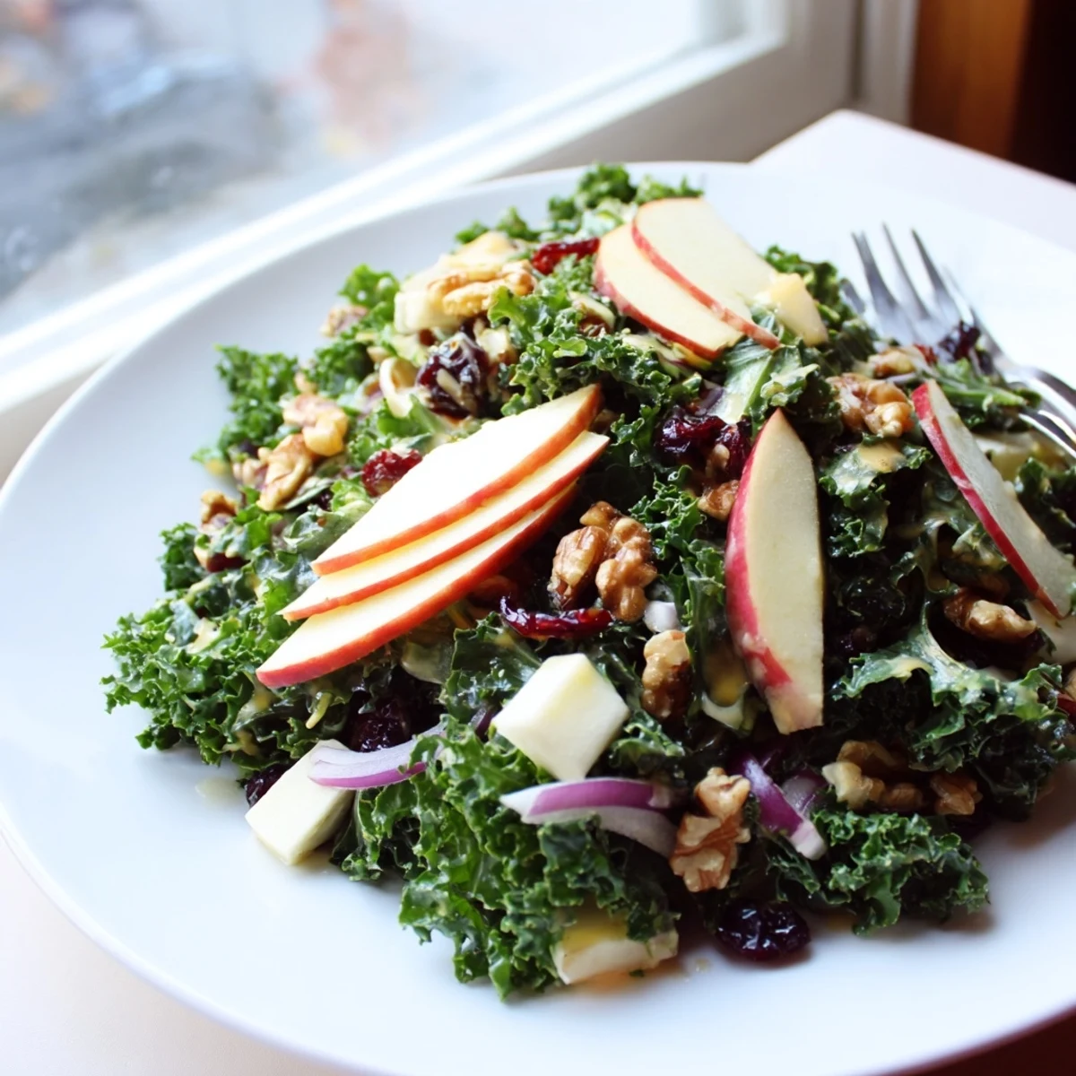 Festive Winter Kale Salad with Apple and Cheddar topped with toasted walnuts, dried cranberries, and a glossy maple-Dijon vinaigrette.