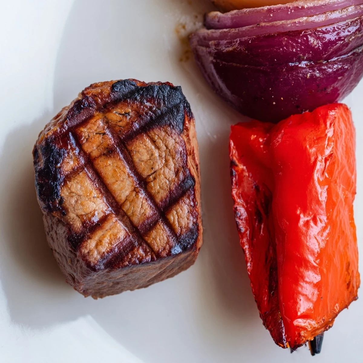 Sizzling Beef Kebabs with Peppers and Onions fresh off the grill, showcasing juicy marinated beef cubes alongside charred red and yellow bell pepper pieces and tender onion wedges on a metal skewer.