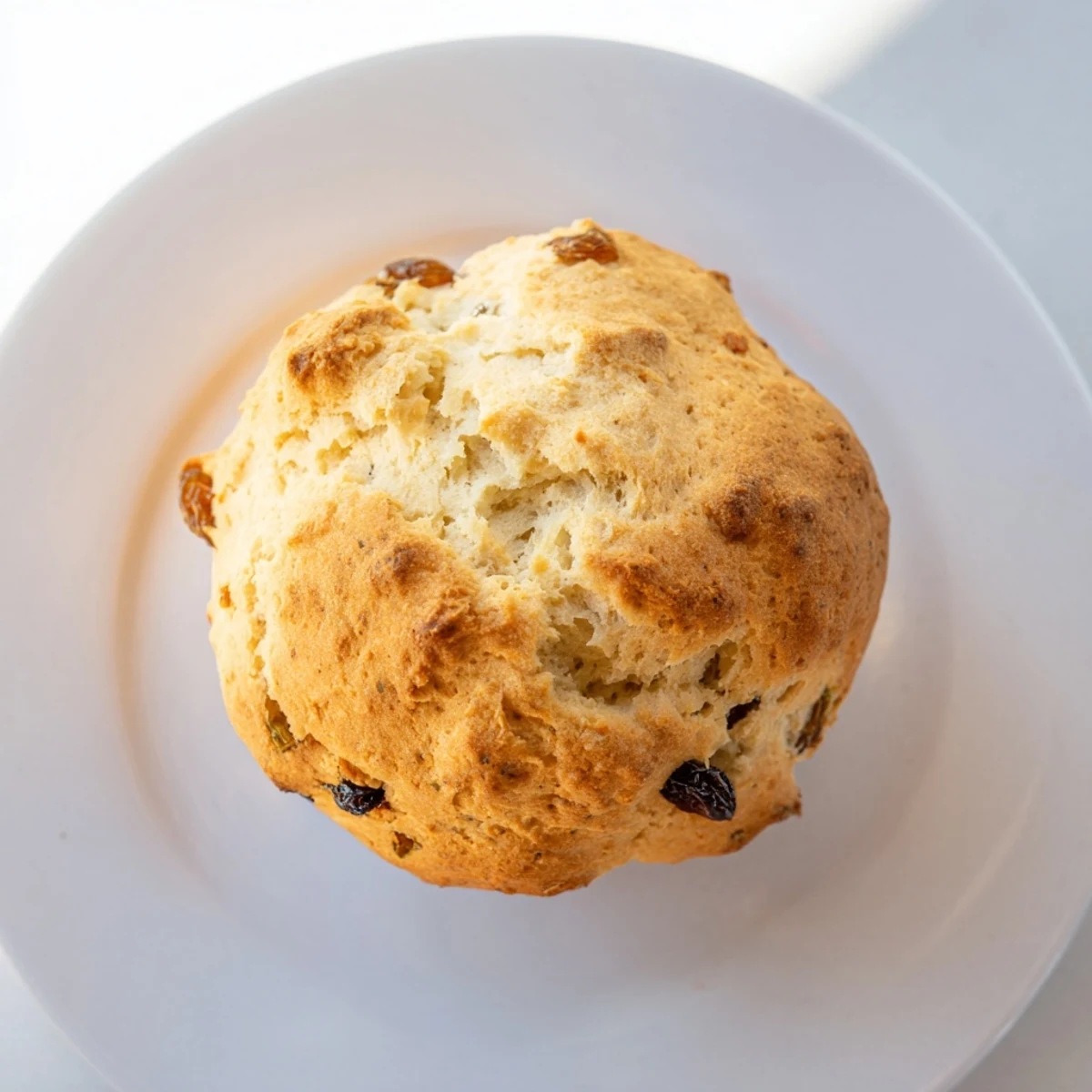 Golden-brown Irish Soda Bread Muffins studded with plump raisins, ready to serve warm with a pat of butter.