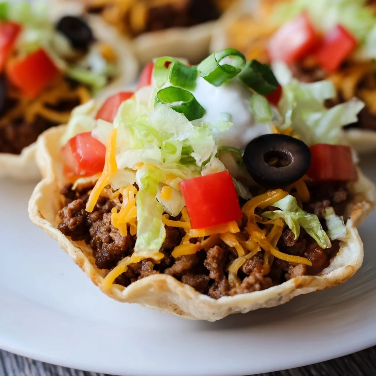 Golden brown, crispy Touchdown Taco Cups filled with seasoned beef and melted cheddar, topped with fresh lettuce and a dollop of sour cream.