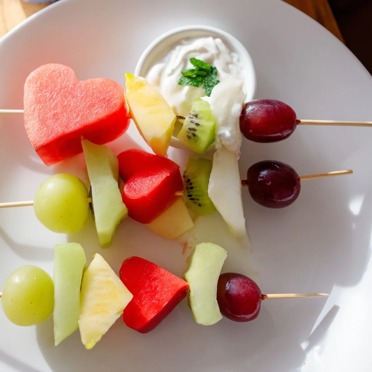 Vibrant fresh fruit hearts, including pineapple, watermelon, and strawberries, skewered for a sweet snack and paired with a honey-kissed yogurt dip.