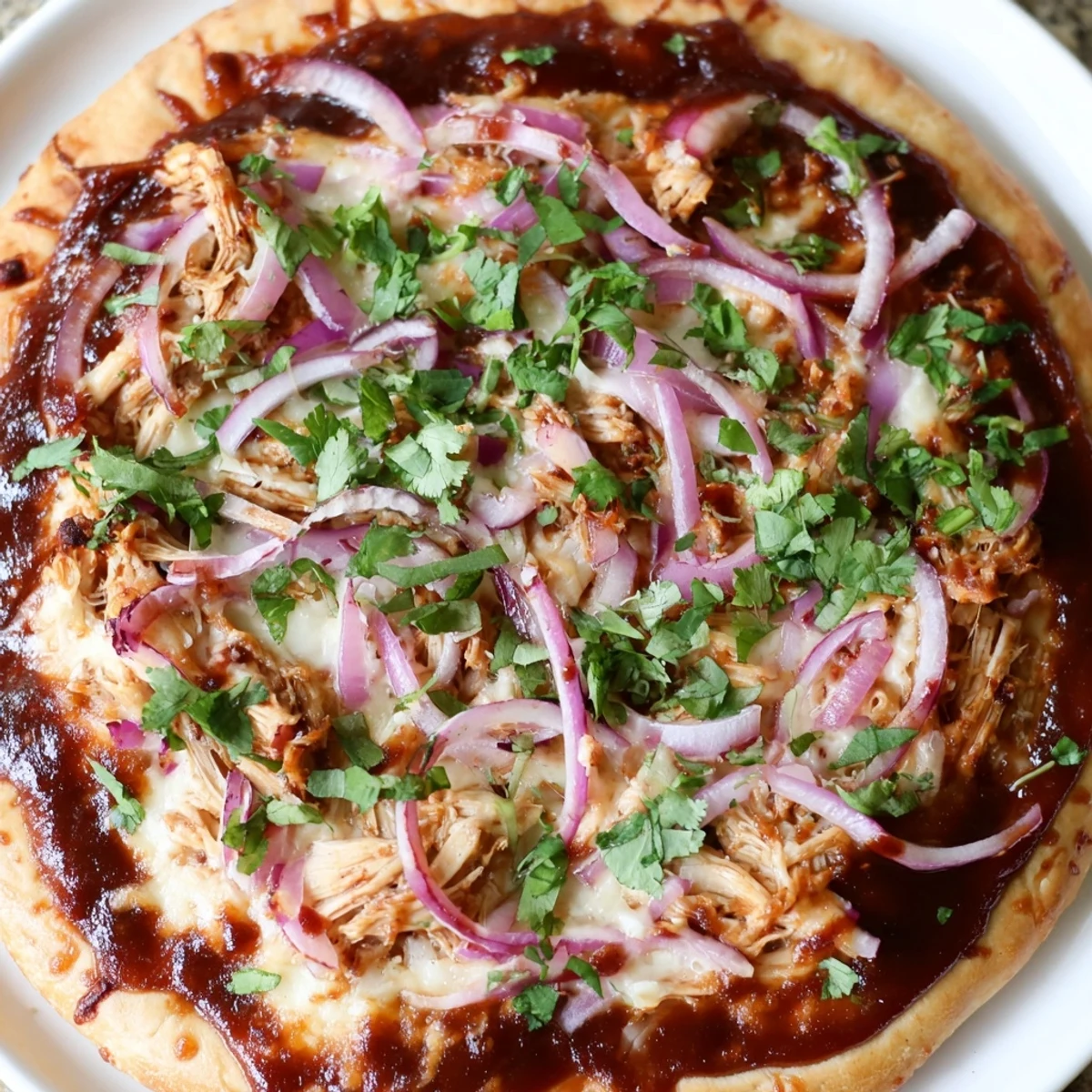 A close-up of BBQ Chicken Pizza with Red Onion and Cilantro, showcasing melted cheese and smoky sauce on a golden crust.
