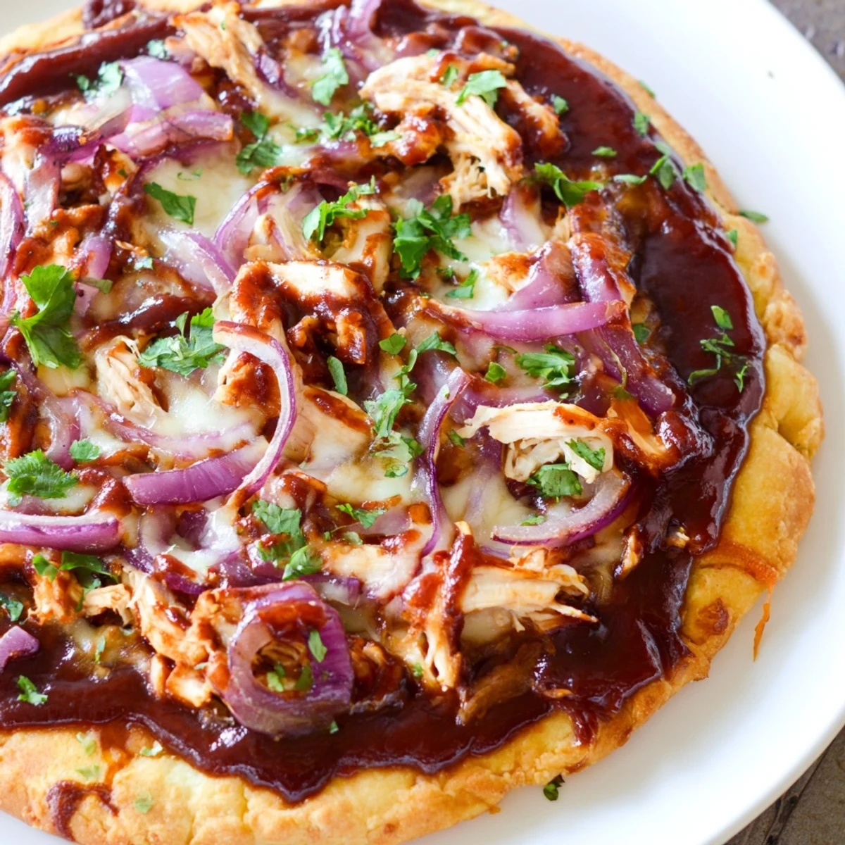 Golden BBQ Chicken Pizza with Red Onion and Cilantro, served hot with gooey cheese and tender chicken on a rustic table.