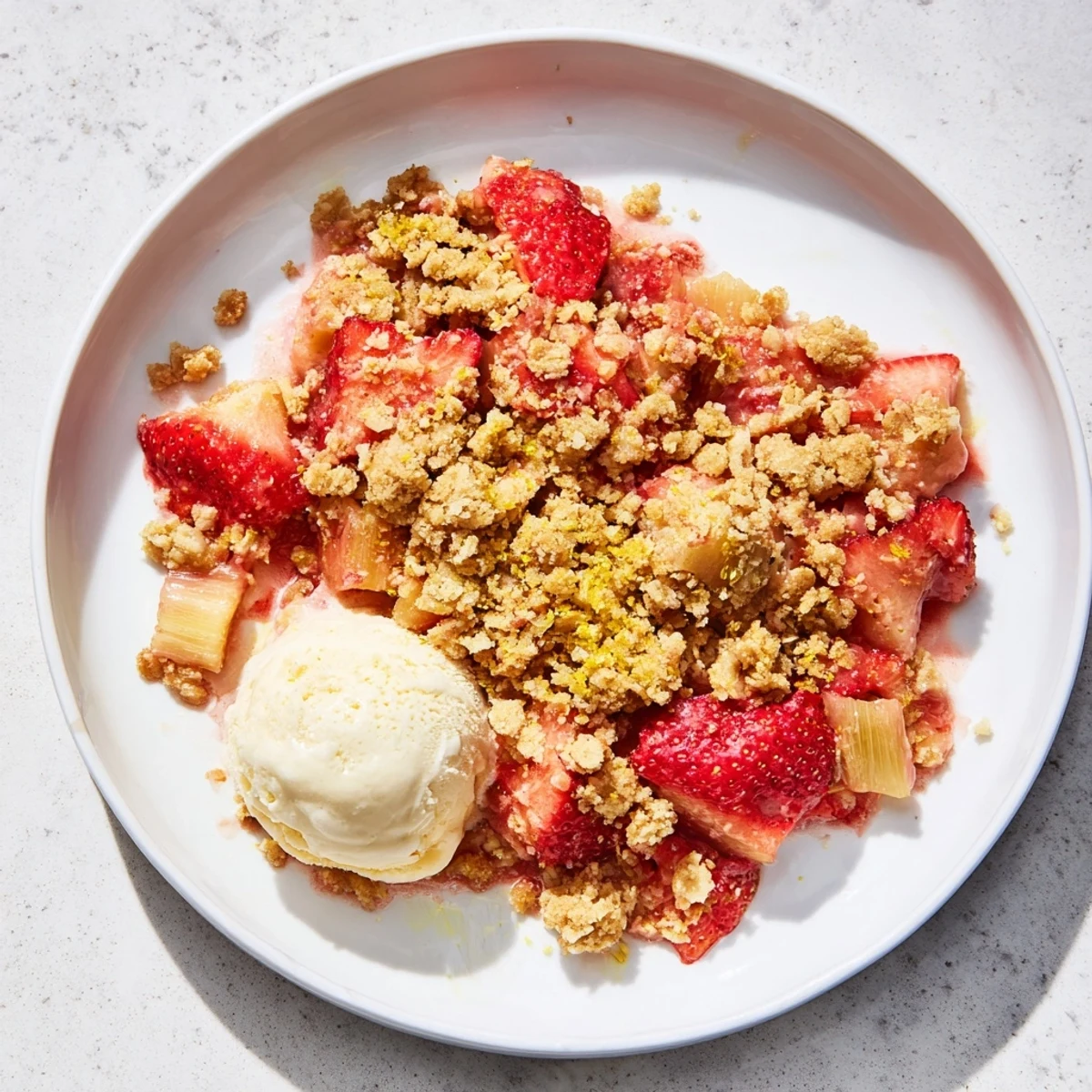 Warm Strawberry Rhubarb Crumble with bubbly fruit filling and vanilla ice cream.