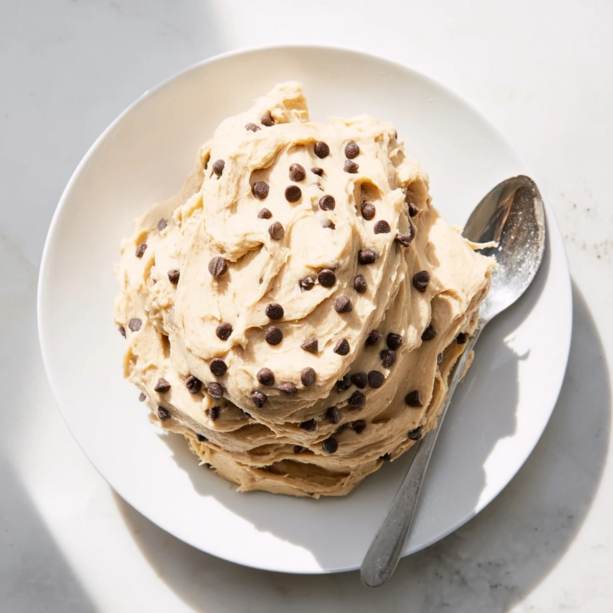 This Cookie Dough Frosting recipe shows a smooth, light brown sugar frosting ready for spreading on cooled brownies.