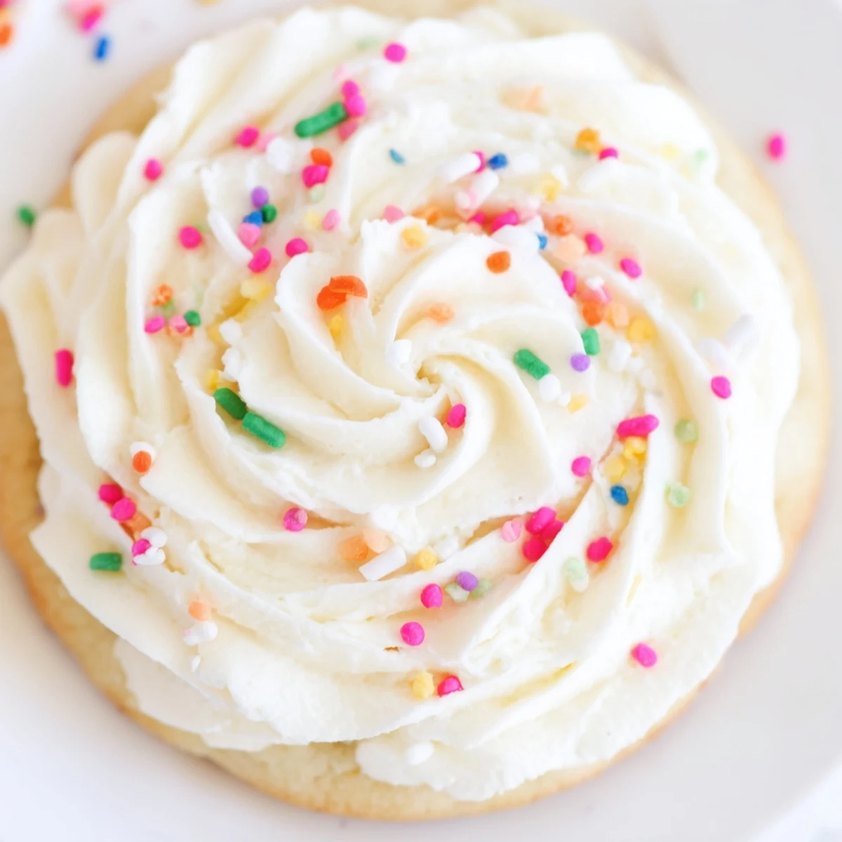 Top-down view of Walmart-Style Sugar Cookies with Buttercream Frosting, arranged on a marble counter with a crinkled napkin and extra sprinkles nearby.
