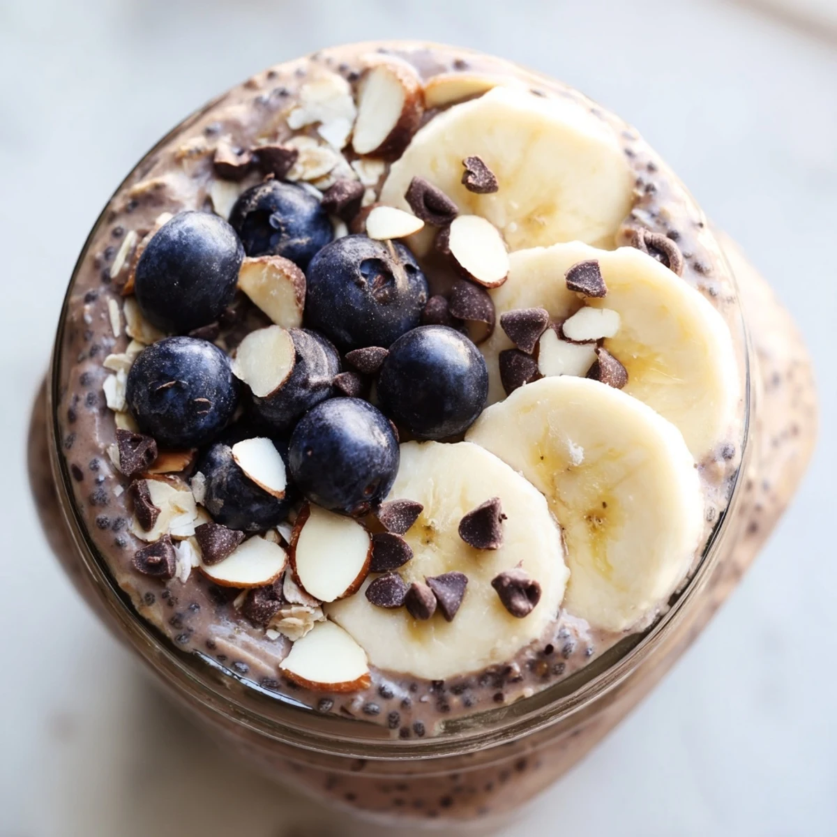 This jar of Ultimate Healthy Chocolate Overnight Oats shows creamy texture with fresh berries and a drizzle of maple syrup.