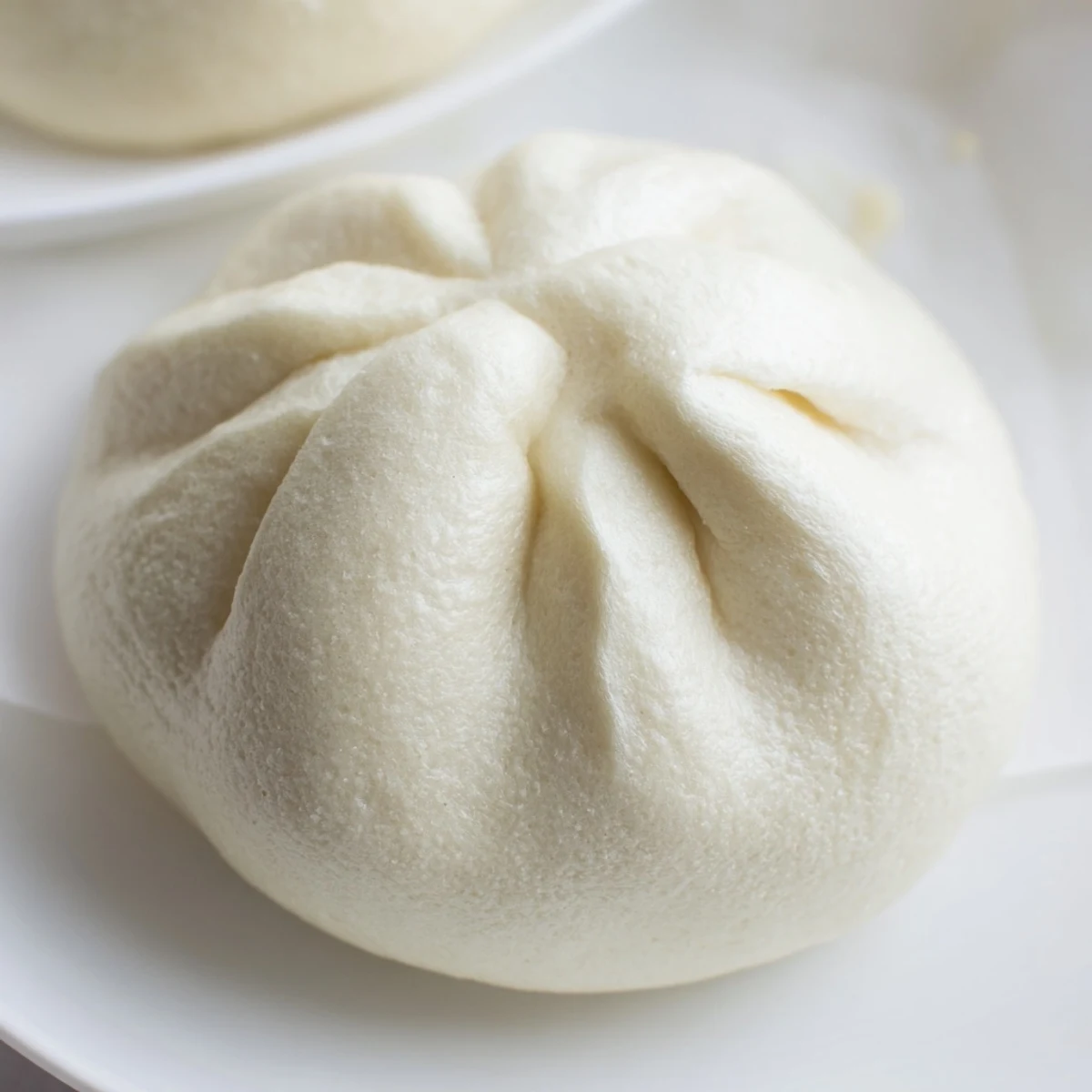 A warm, fluffy Banh Bao bun filled with savory pork, shiitake mushrooms, and hard-boiled egg on a plate.