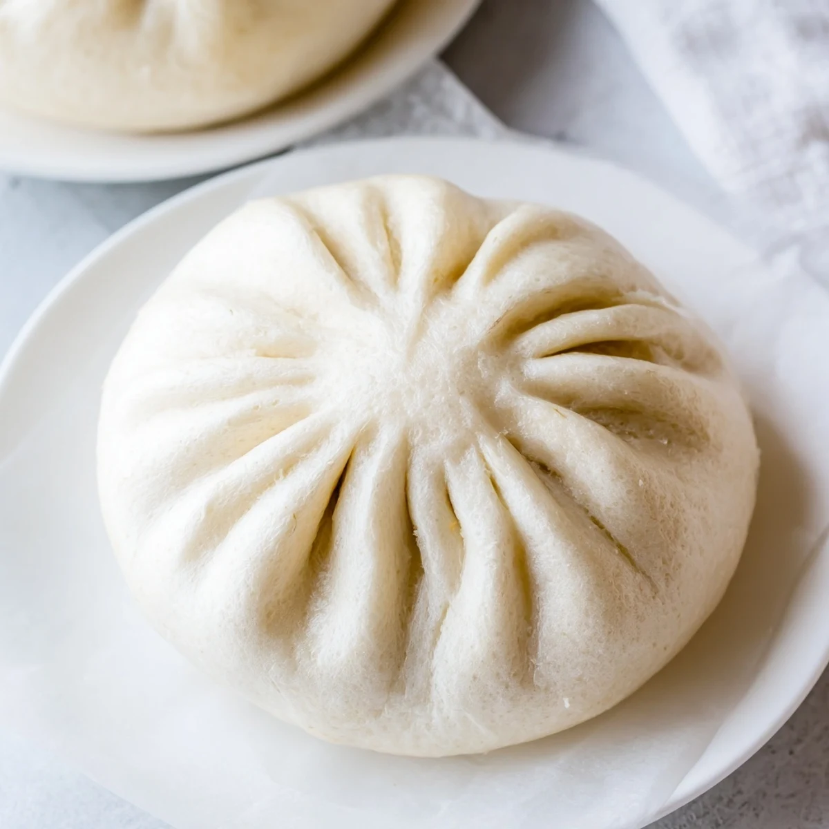 Close-up of a Vietnamese steamed bun, revealing tender pork and chopped Chinese sausage inside the dough.