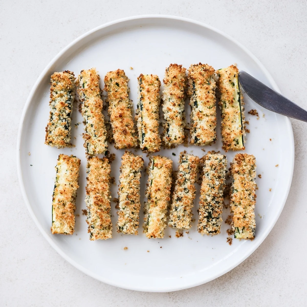 These zucchini fries are served with a small bowl of sugar-free marinara sauce for a delicious keto-friendly snack.