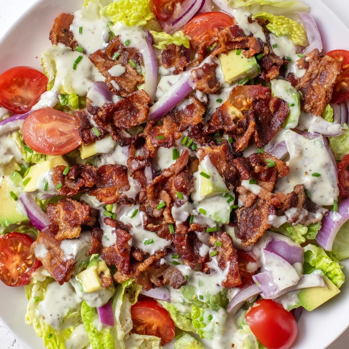 Crispy Bacon Keto BLT Salad with juicy tomatoes, creamy avocado, and crunchy romaine in a tangy dressing.