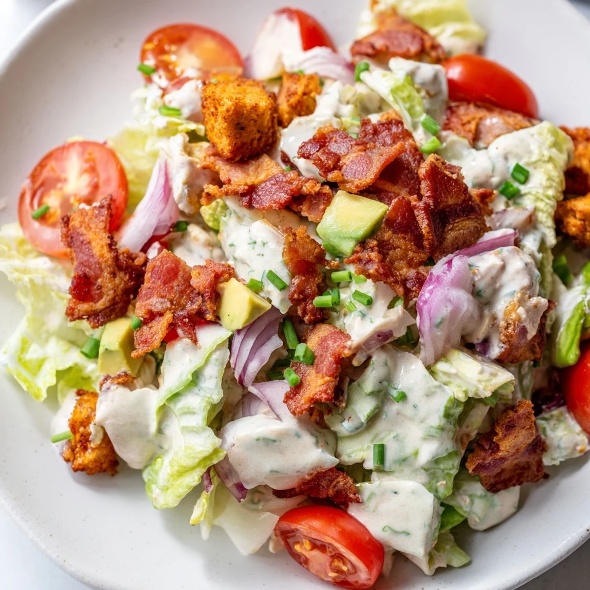 A bowl of Crispy Bacon Keto BLT Salad showcasing golden bacon crumbles and sliced red onion on fresh greens.