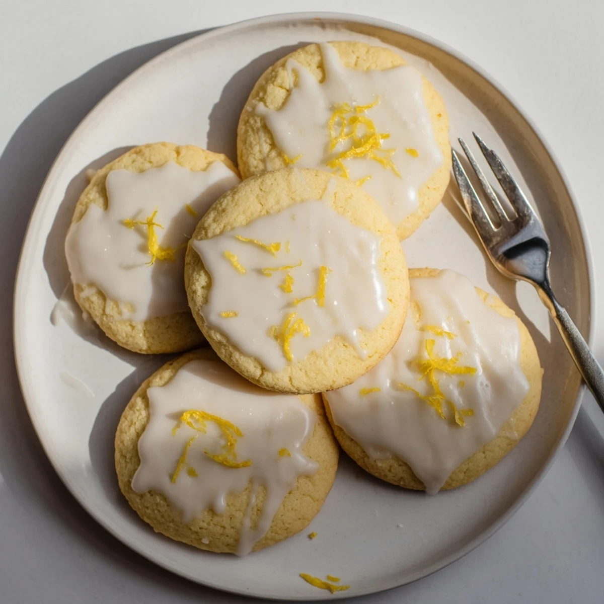 Freshly baked Limoncello cookies on a wire rack with a glossy lemon glaze and zest garnish, perfect for spring gatherings.