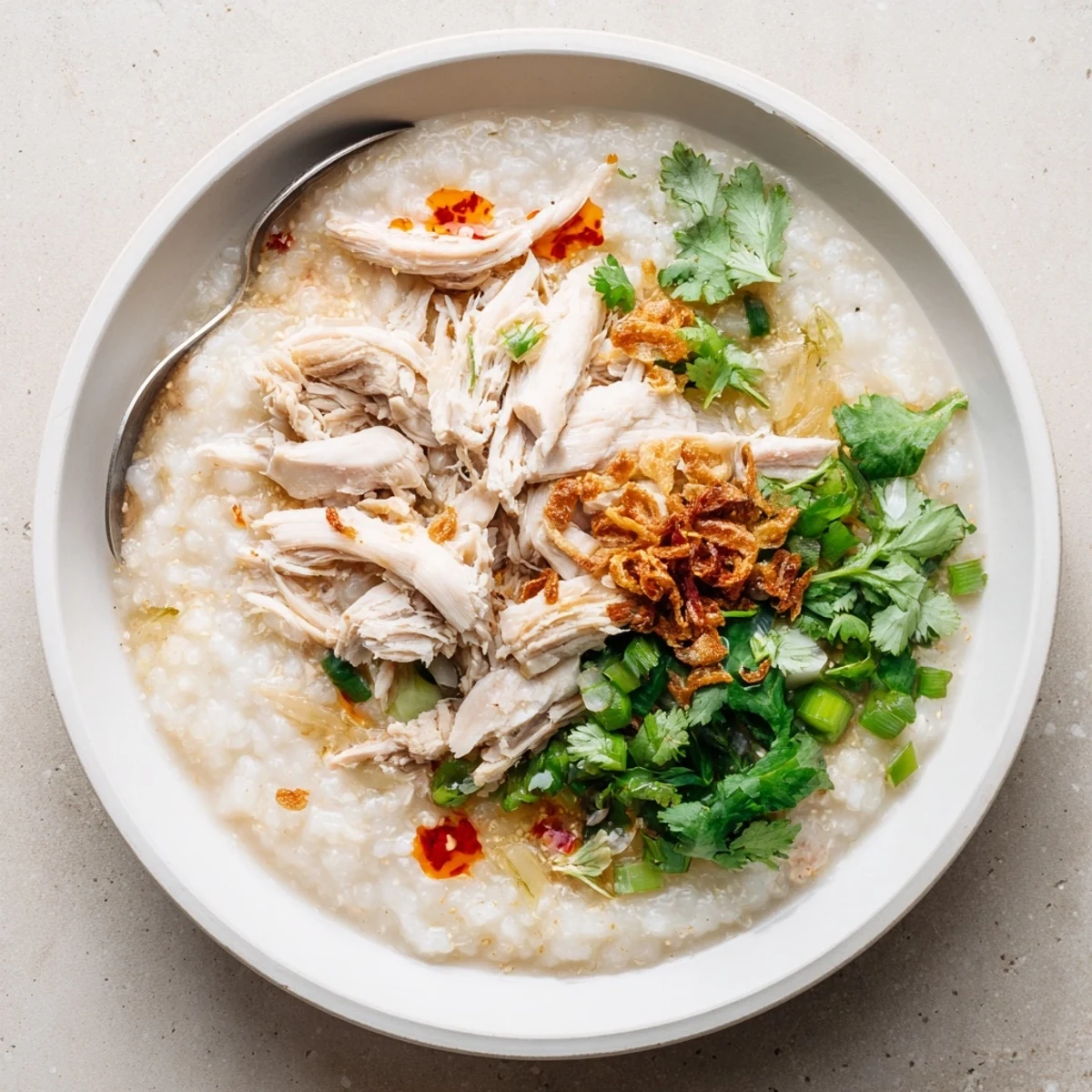Creamy leftover Thanksgiving turkey congee topped with scallions, cilantro, and crispy shallots in a deep bowl