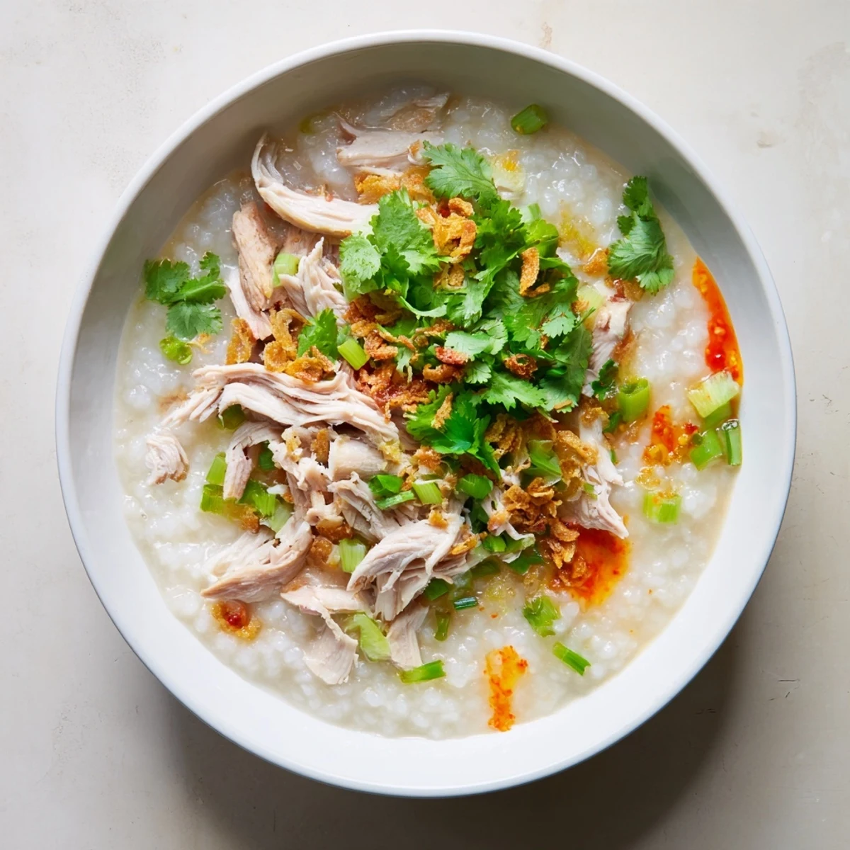 Homemade turkey congee with tender meat pieces, aromatic aromatics, and fresh herbs for a comforting meal