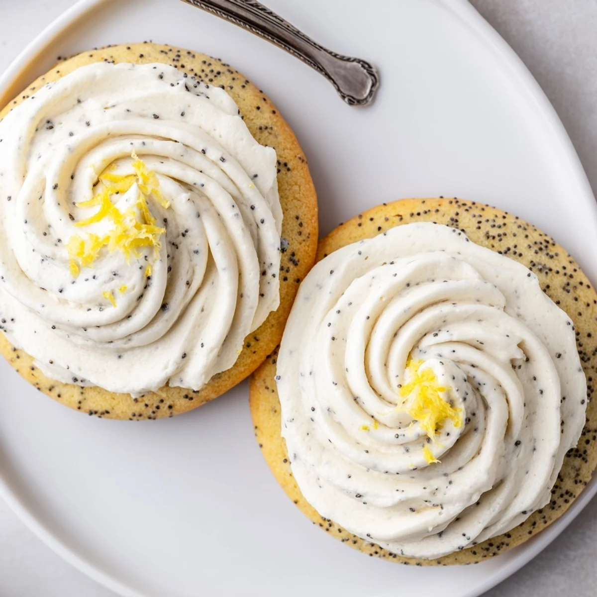 Golden lemon poppy seed cookies with rich cheesecake frosting piped on top