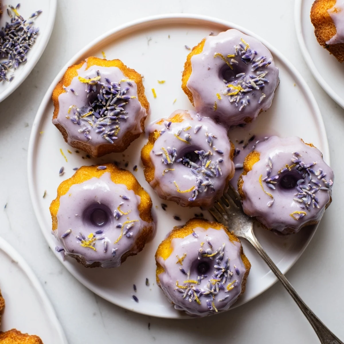 Golden mini lemon cakes with lavender glaze drizzled over freshly baked treats