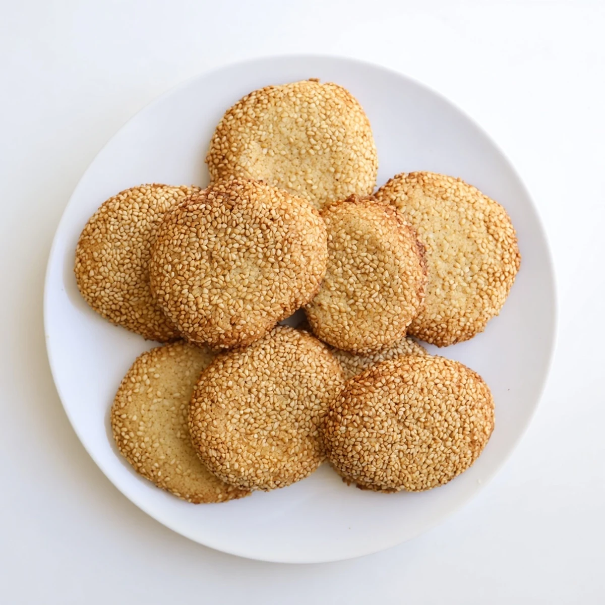 Soft chewy honey sesame cookies stacked together with visible sesame seed speckles throughout
