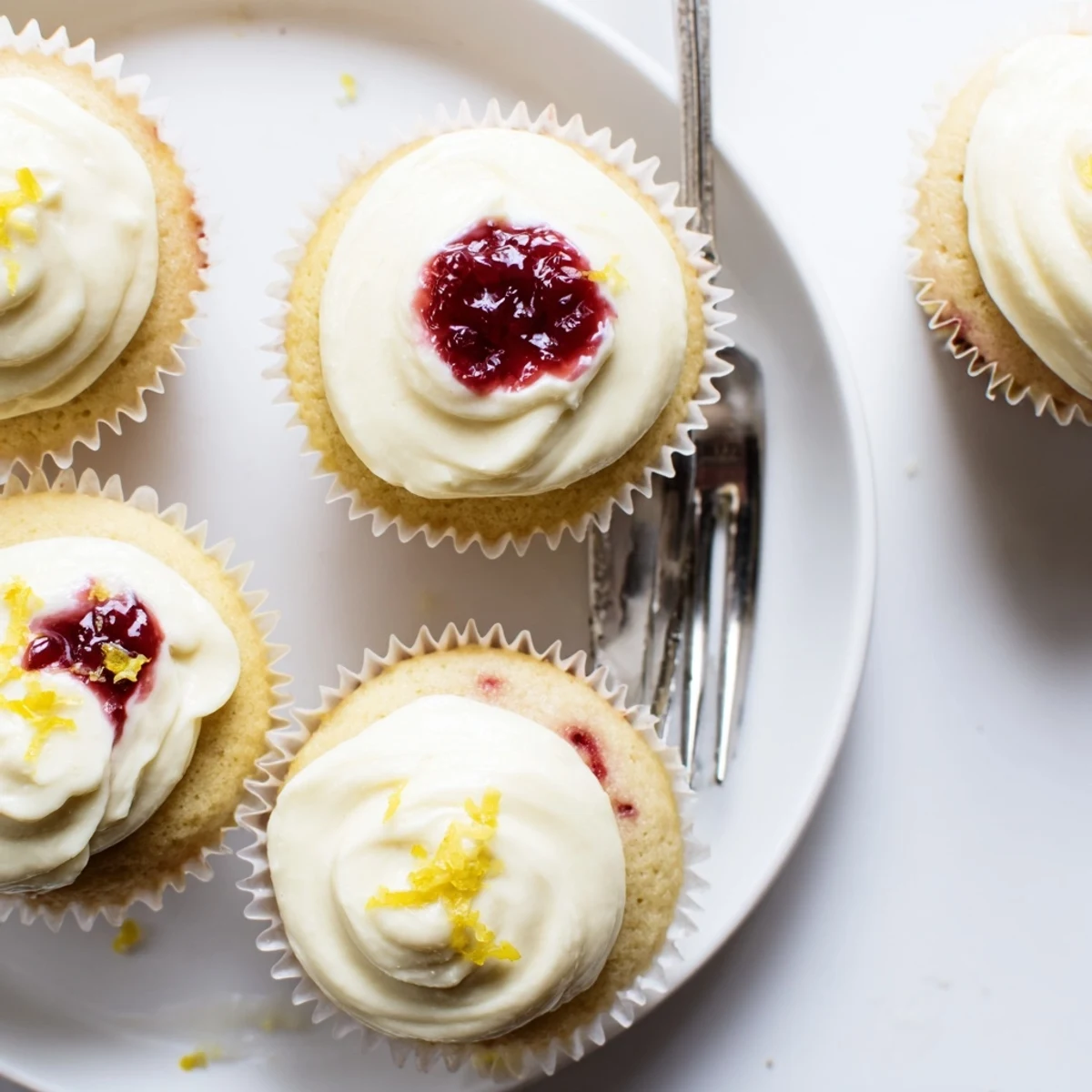 Tender zesty lemon cupcakes filled with tangy raspberry preserves and creamy swirled frosting