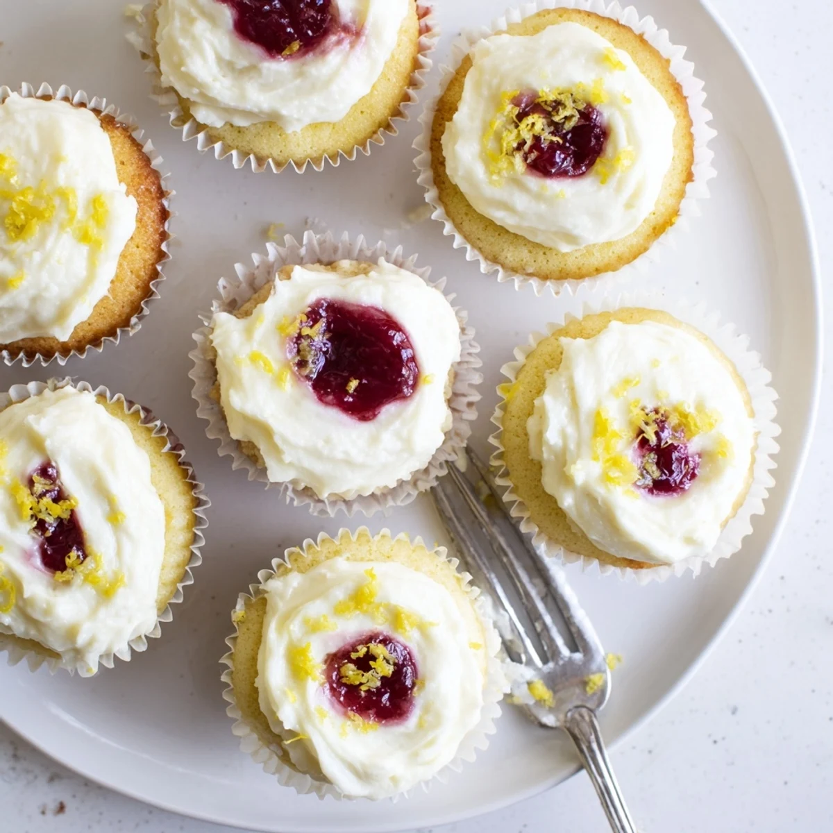 Moist lemon cupcakes with raspberry filling topped with fluffy lemon buttercream frosting