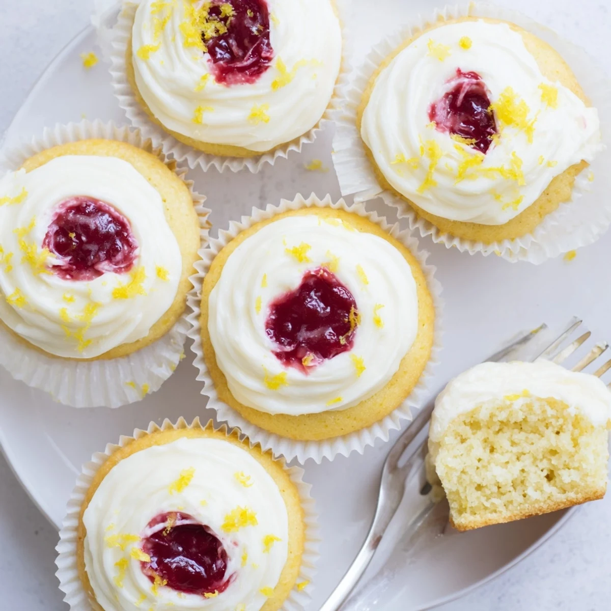 Golden lemon cupcakes stuffed with sweet raspberry jam and finished with bright lemon buttercream