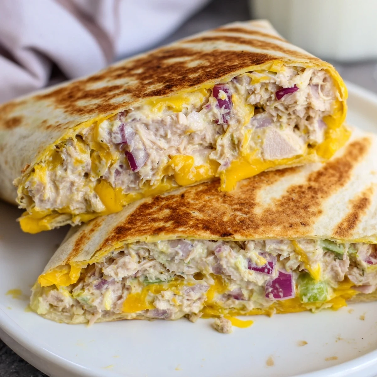 Sliced tuna melt wrap revealing creamy tuna salad and gooey cheese filling