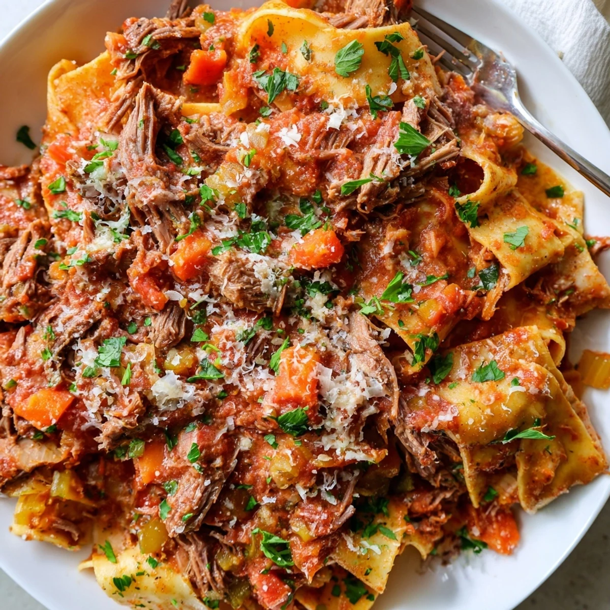 Hearty slow cooker beef ragu featuring fork-tender beef chunks simmered in Italian herbs and tomatoes