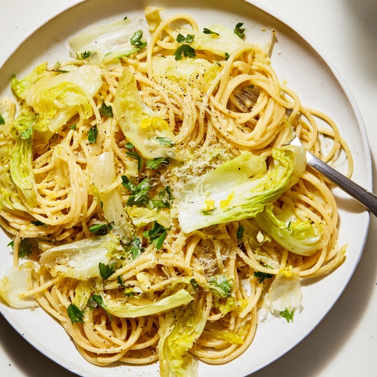 Close up of tender cabbage strands coated in zesty lemon garlic sauce with grated Parmesan