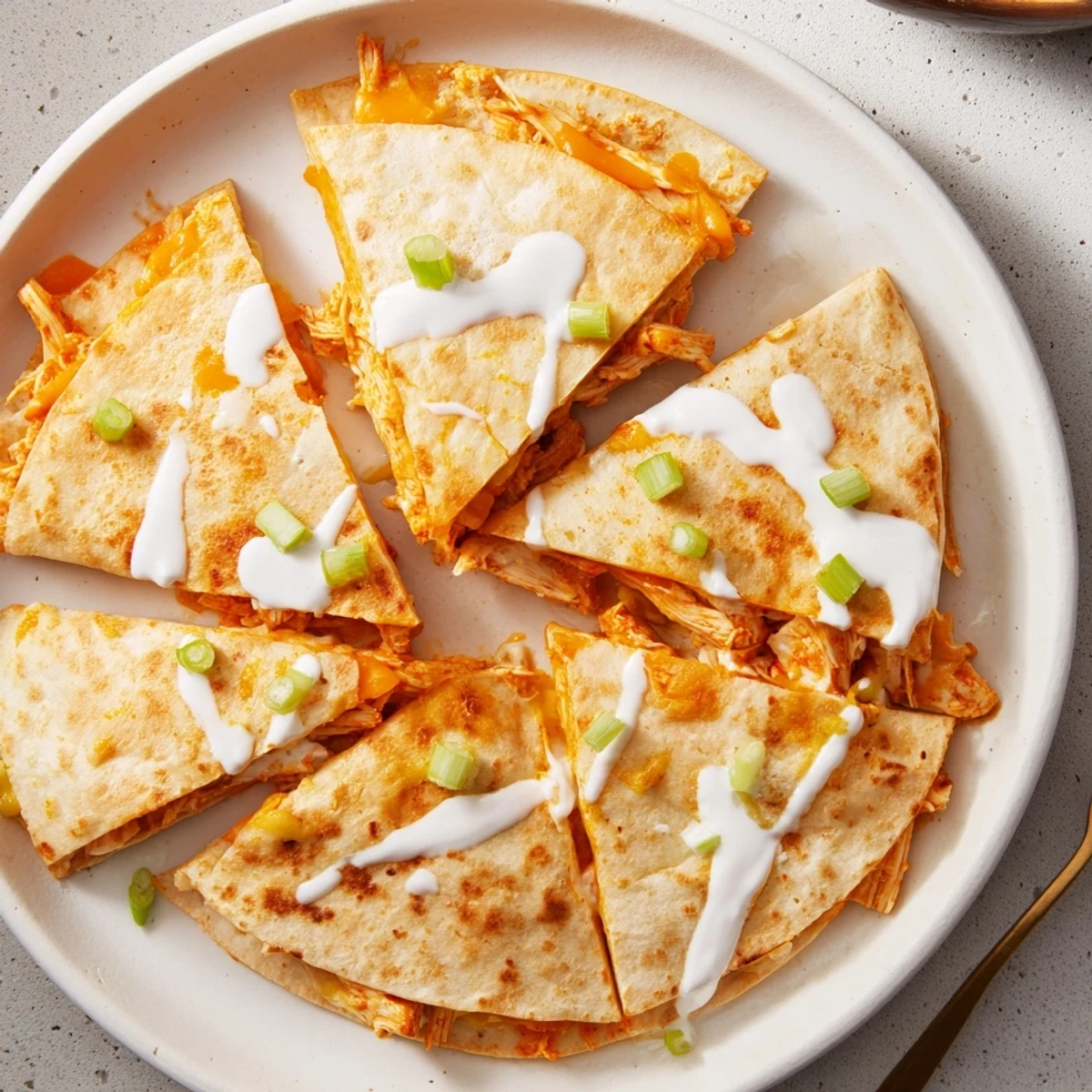Golden brown Buffalo Chicken Quesadillas with melted cheese and white ranch drizzle