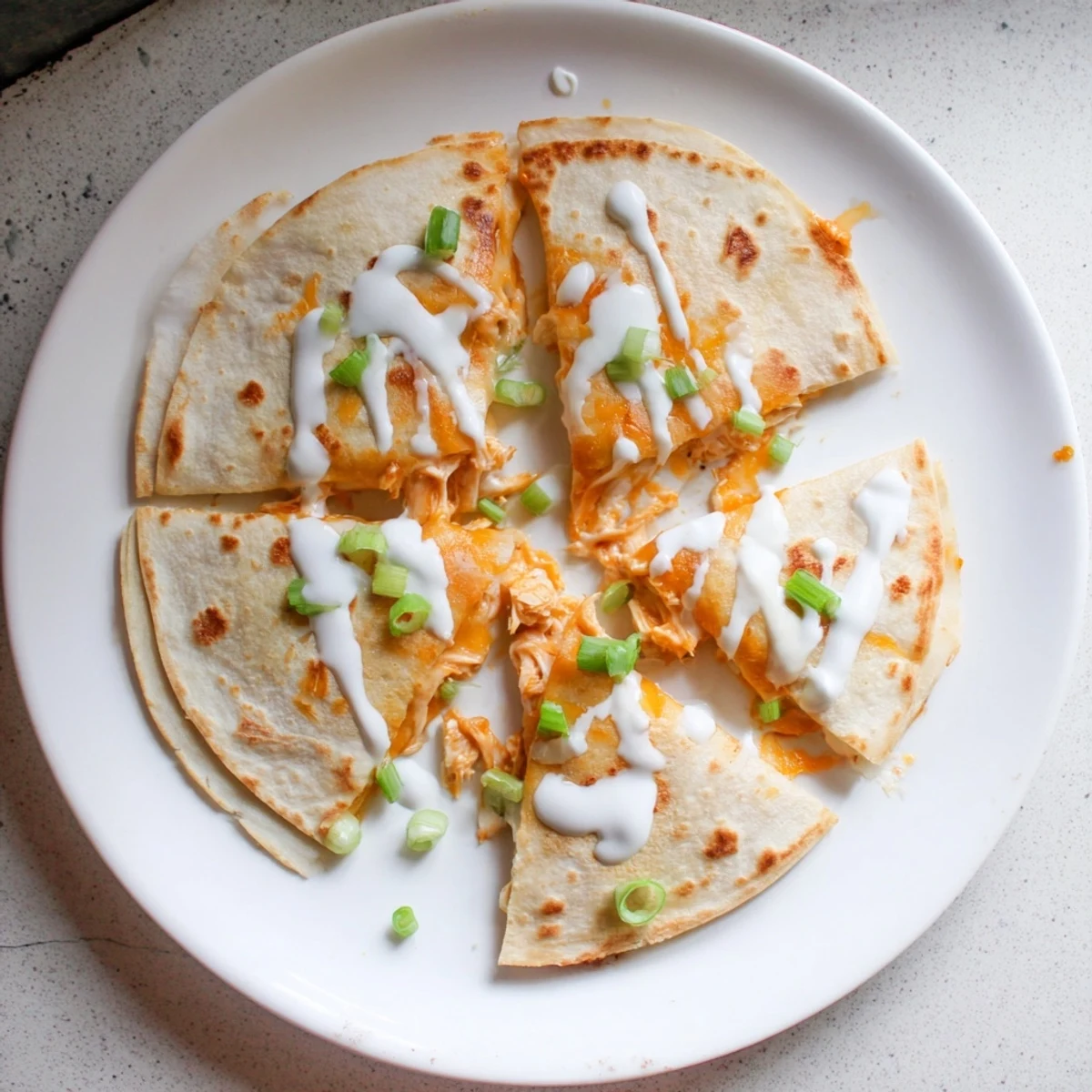 Crispy flour tortilla quesadilla filled with cheesy buffalo chicken and ranch drizzle