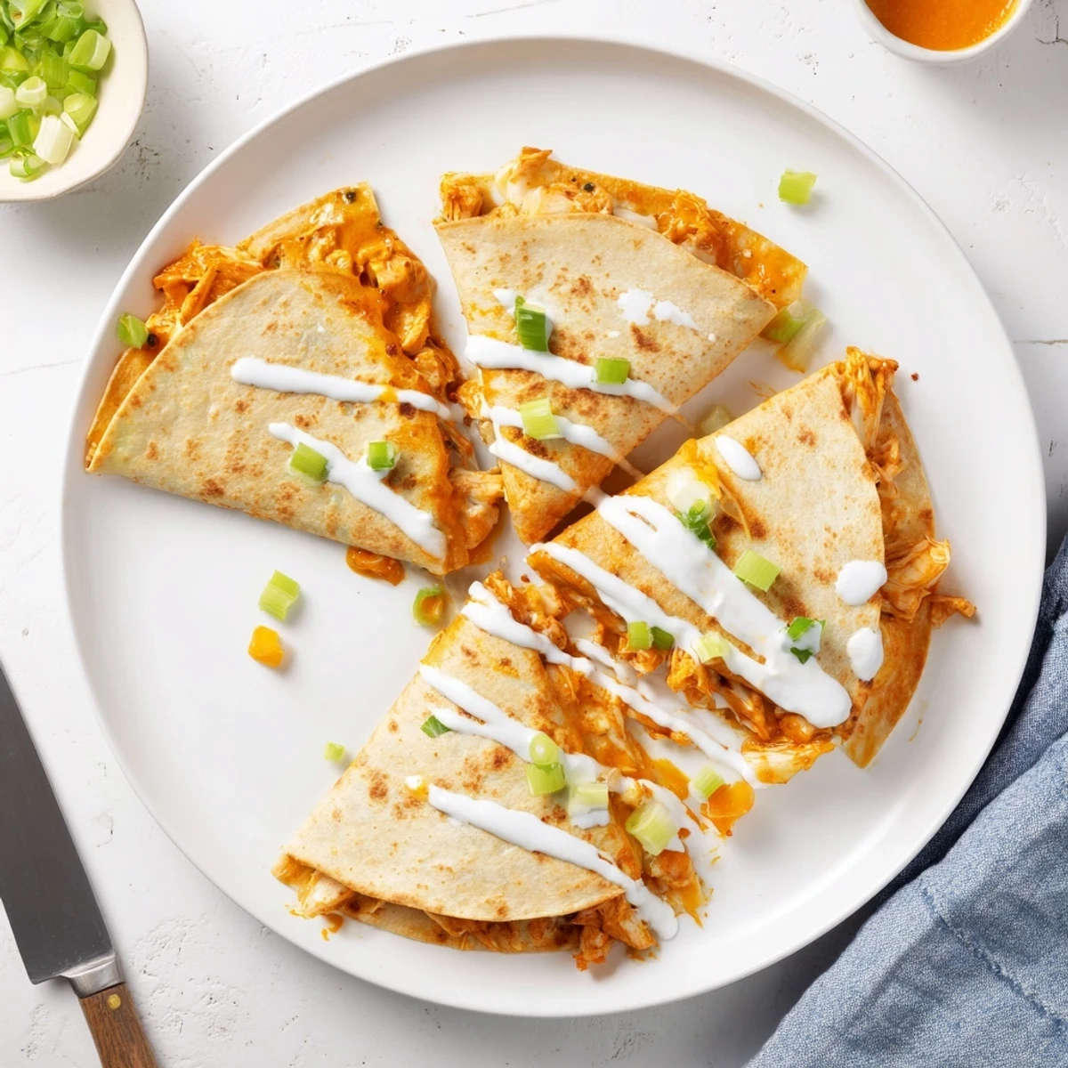 Spicy buffalo chicken quesadillas sliced into wedges topped with cooling ranch sauce