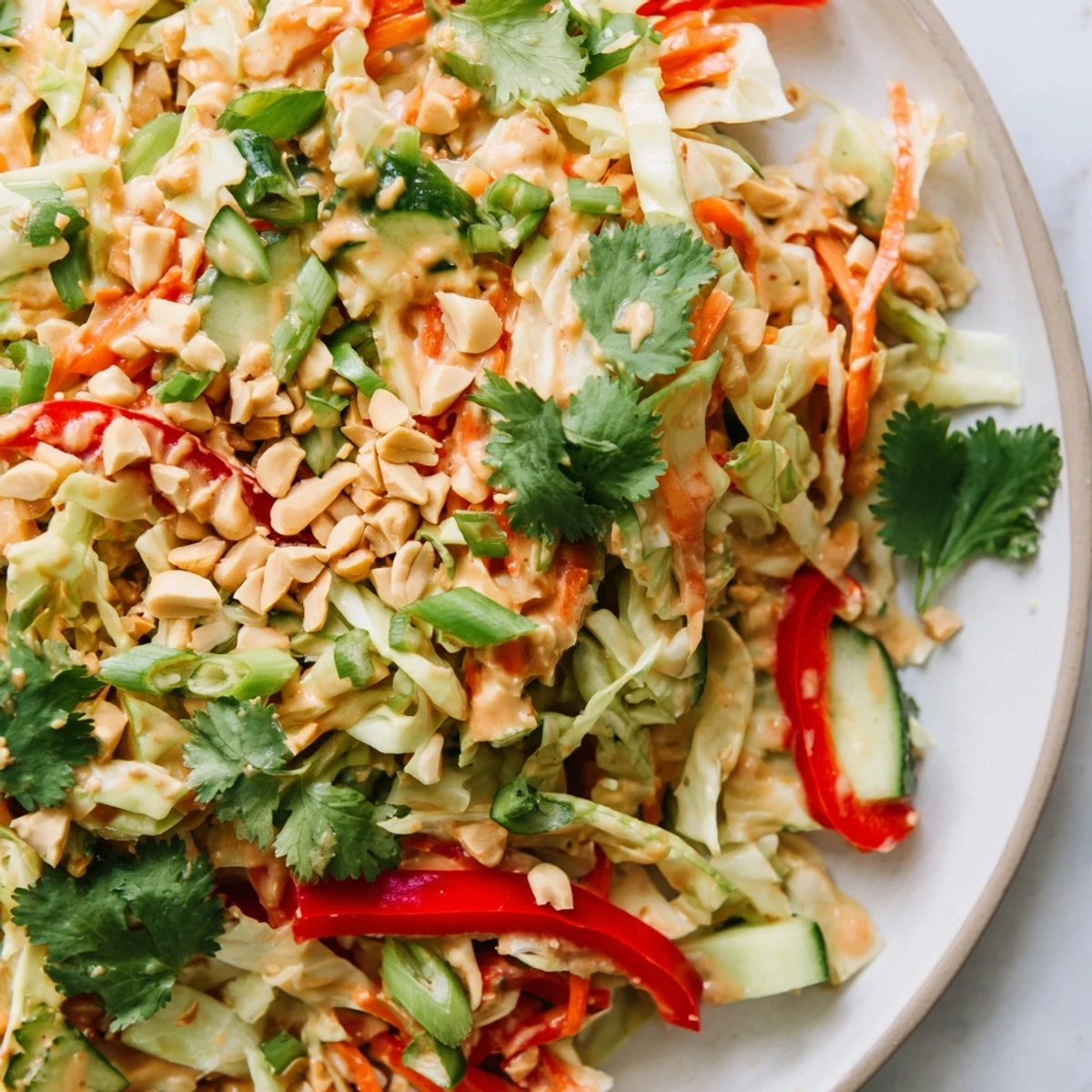 Fresh vegetable salad tossed in rich Thai peanut sauce with shredded cabbage carrots and cilantro