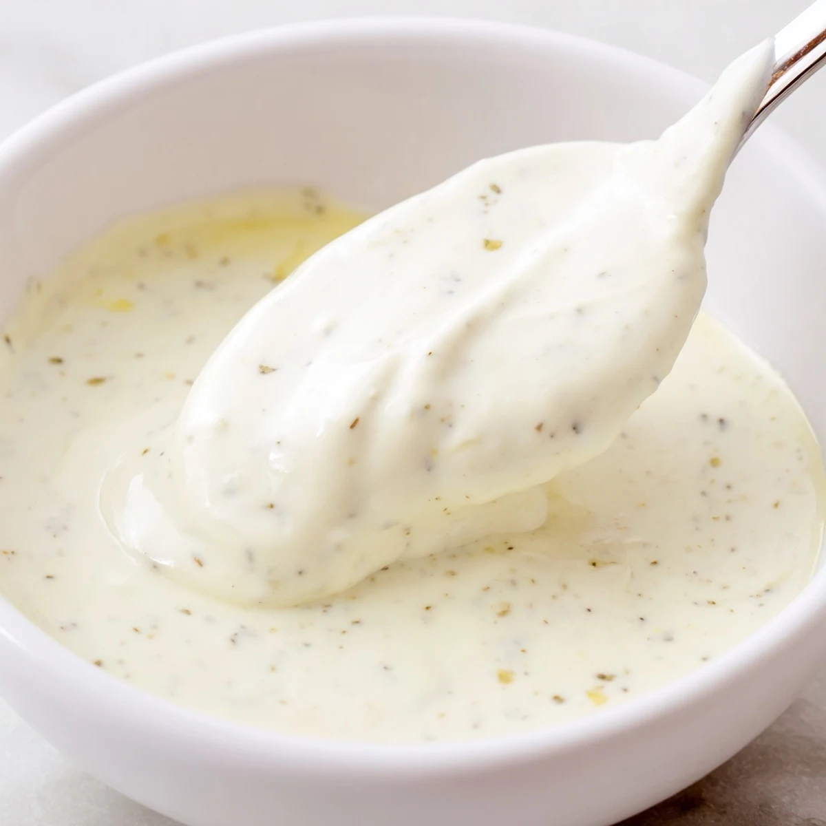 Rich garlic sauce bowl beside warm chicken shawarma wrap with fresh vegetable toppings