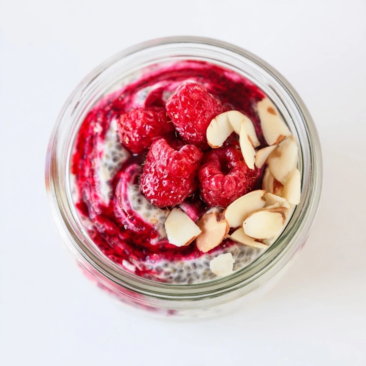 Vegan raspberry chia pudding with maple syrup featuring layers of mashed raspberries and creamy chia base