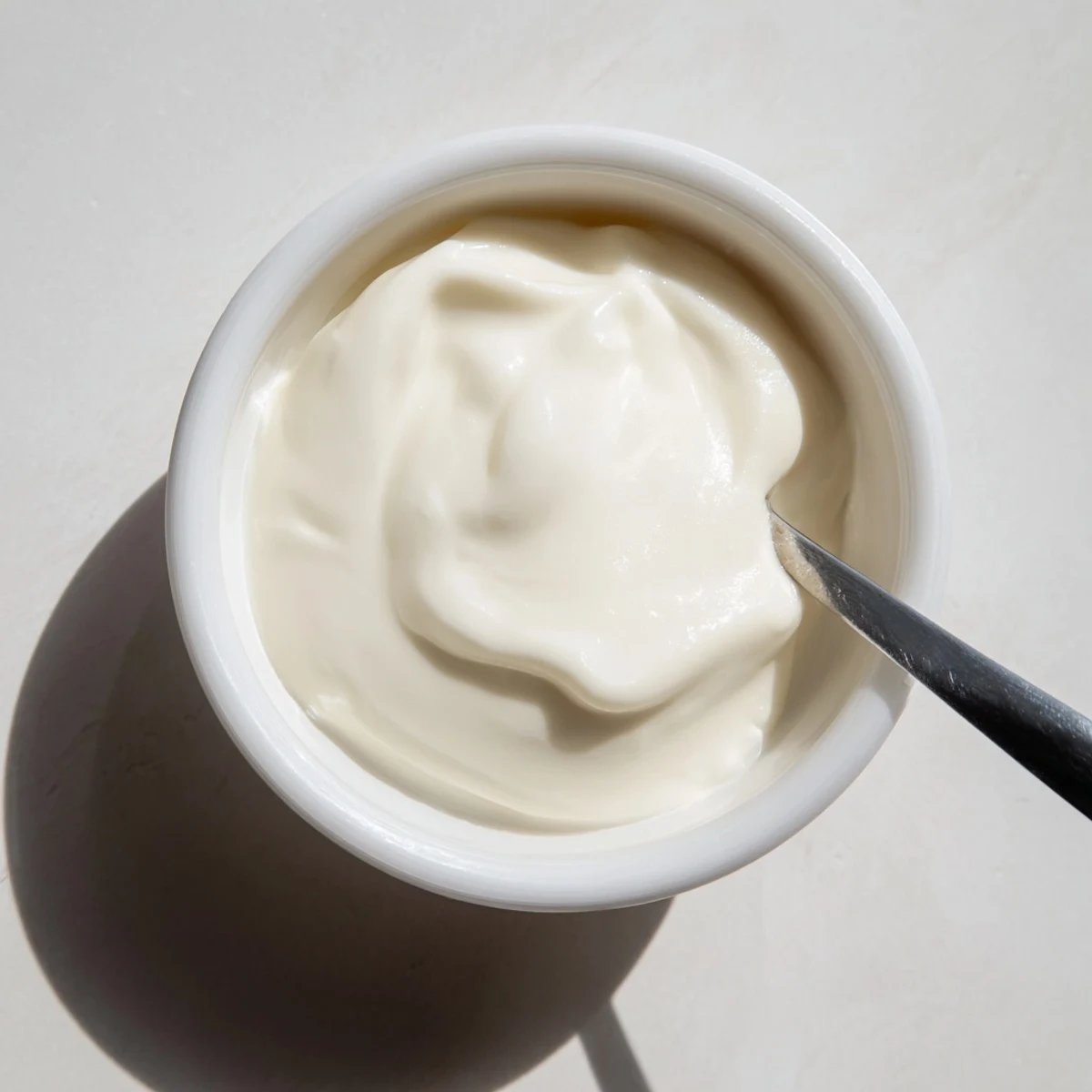 Spoonful of rich tangy Greek yogurt plated with granola and sliced strawberries for breakfast