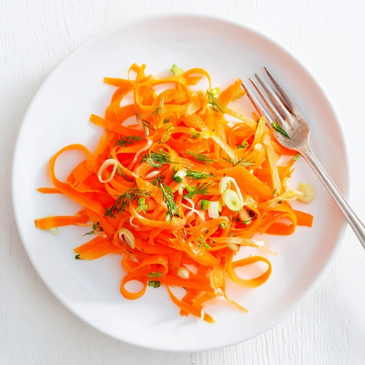 Crisp marinated carrot salad glistening with lemon dill dressing in a serving bowl