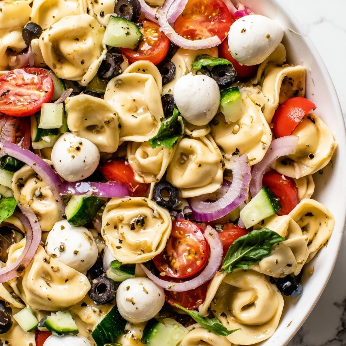 Colorful tortellini salad with cherry tomatoes, cucumber, and mozzarella in zesty Italian dressing
