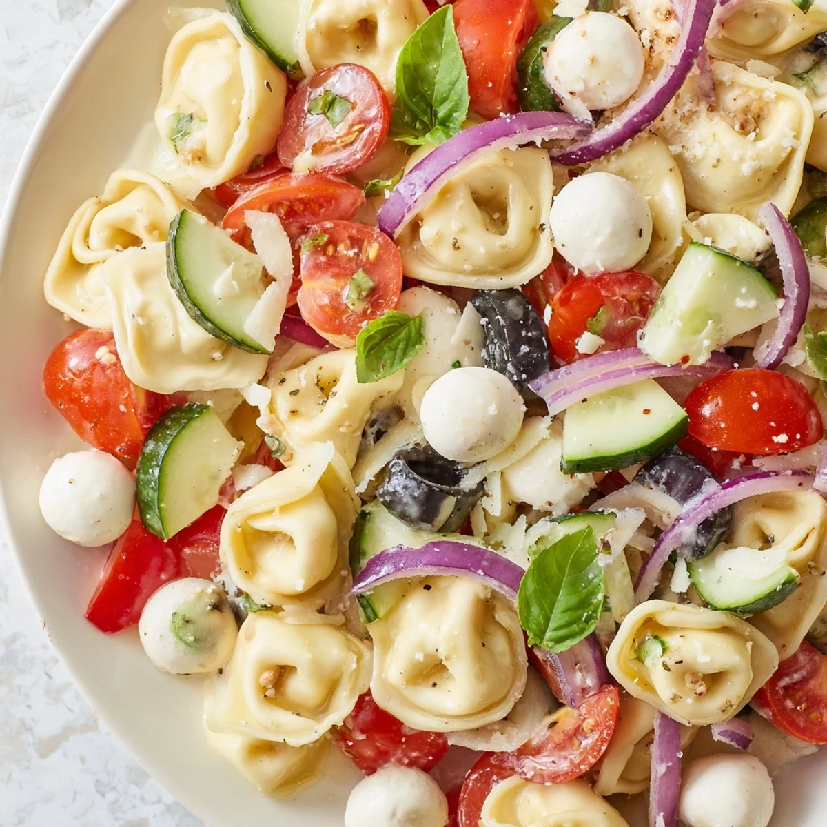 Creamy cheese tortellini salad tossed with crisp vegetables and fresh basil leaves