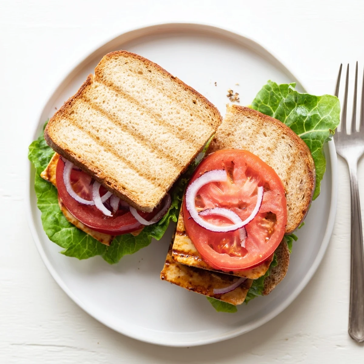 Smoky Tofu Lettuce Tomato TLT Sandwich stacked on toasted sourdough with juicy red tomatoes
