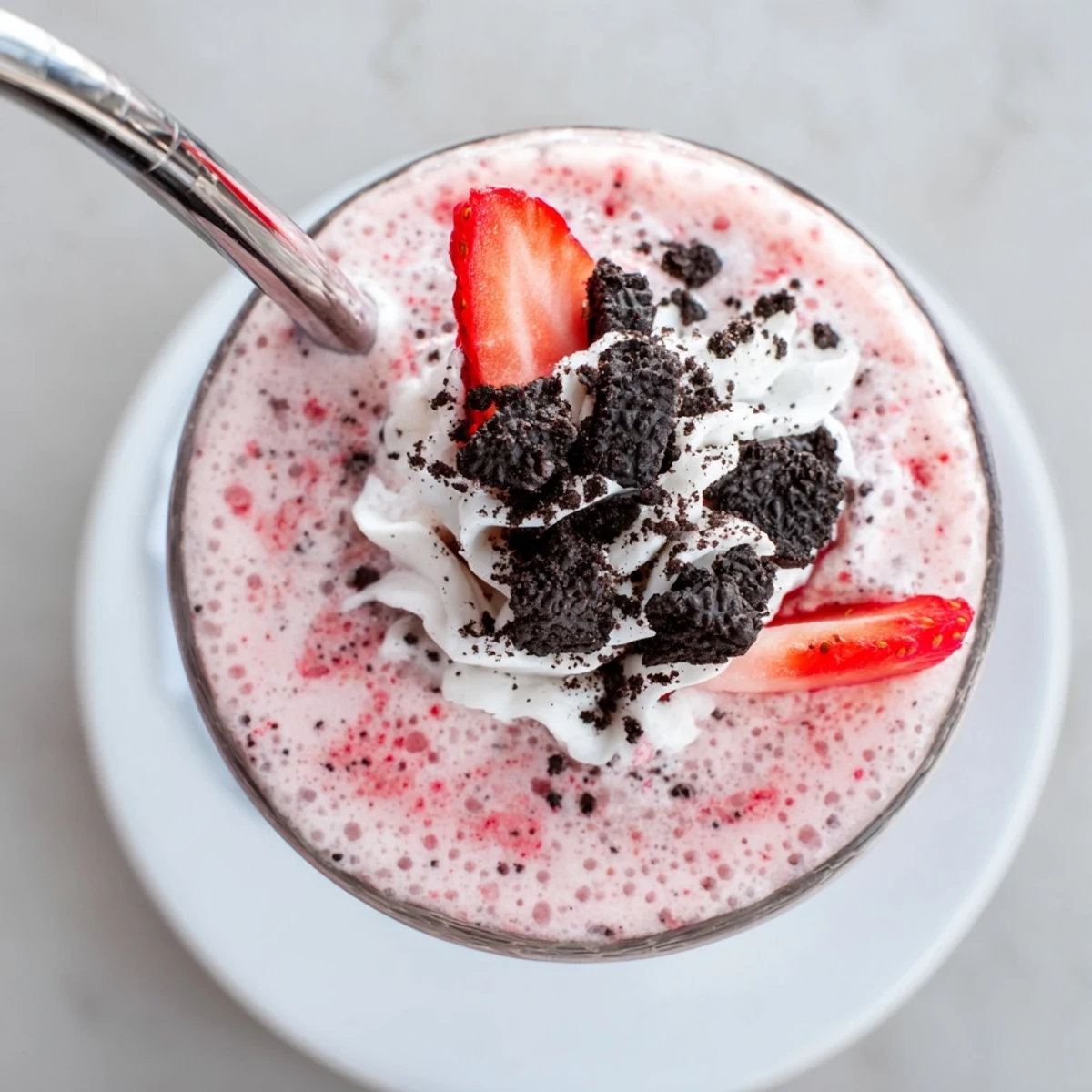 Two glasses of creamy strawberry Oreo milkshake garnished with fresh strawberry slices