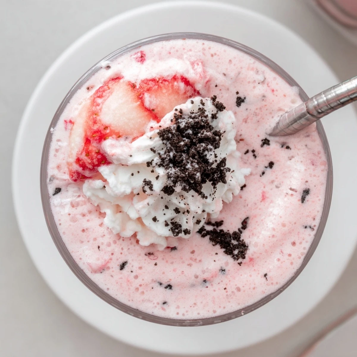 Chilled strawberry Oreo milkshake drizzled with crushed Oreos on a tall glass rim