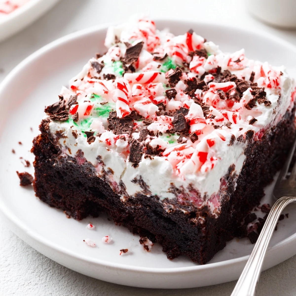 Sliced Peppermint Poke Cake showing minty pudding filling and chocolate shavings