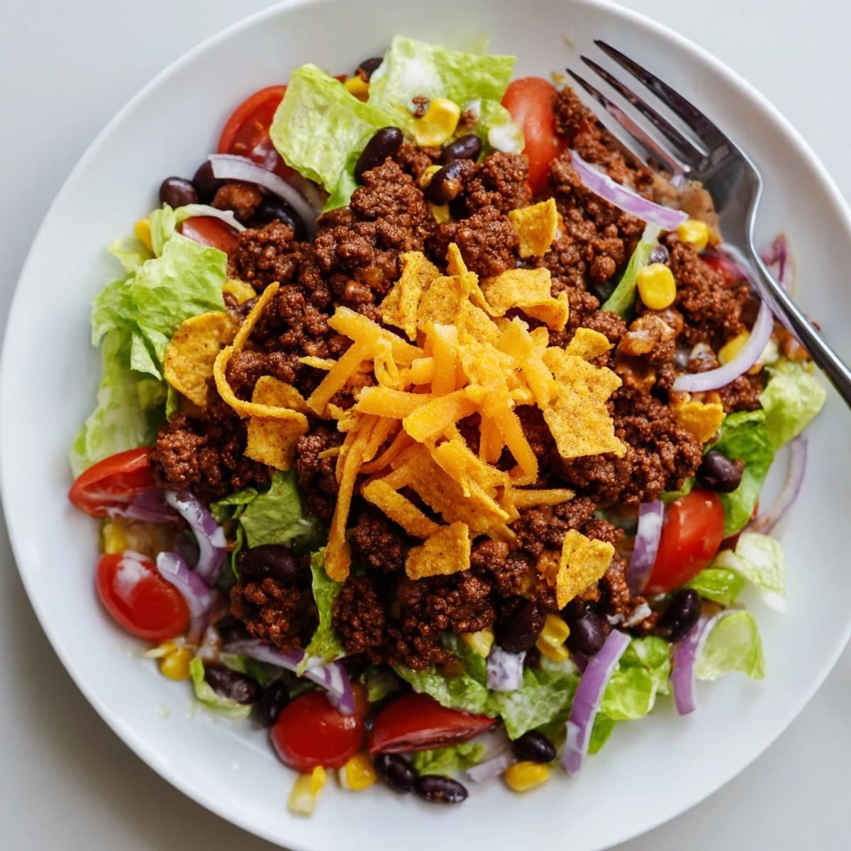 Warm seasoned beef atop Simple Doritos Taco Salad, crisp lettuce and tangy tomatoes